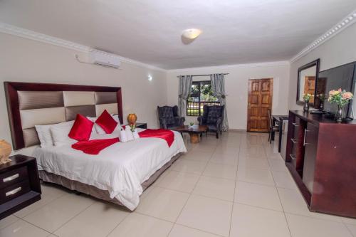 a bedroom with a large bed with red pillows at ASANTE MOUNTAIN LODGE in Hazyview