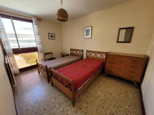 une chambre avec un lit, une commode et une fenêtre dans l'établissement Coeur de ville appartement t3 pour 6 personnes N35, à La Grande Motte