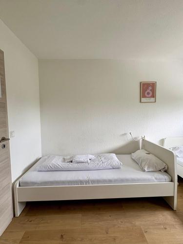 una cama en una habitación con una pared blanca en kleine und charmante Monteurs Unterkunft D, en Karlsruhe