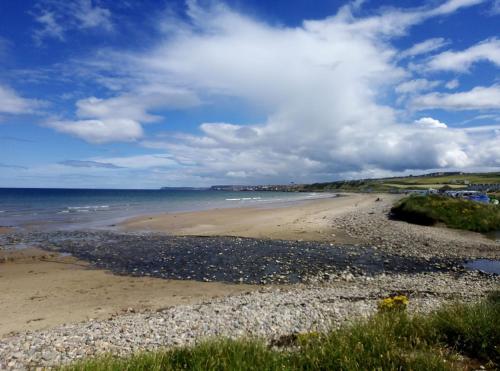 a beach with rocks and the ocean on a cloudy day at Seabreeze in Whitehills