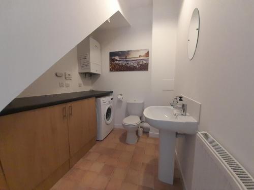 a white bathroom with a sink and a toilet at Seabreeze in Whitehills