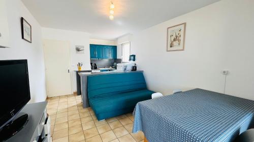 - une cuisine avec un canapé bleu dans une chambre dans l'établissement Sable et mer, T2 des pins, à Saint-Jean-de-Monts