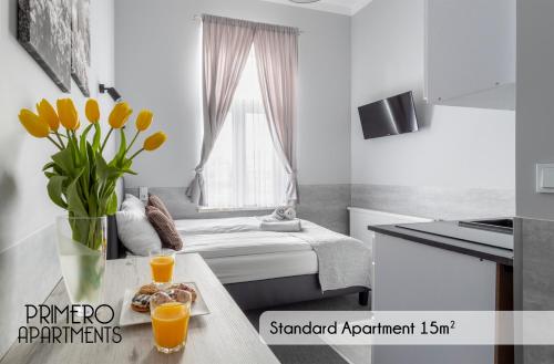 a room with a bed and two glasses of orange juice at PRIMERO Elegant Apartments KRAKÓW Old Town in Kraków