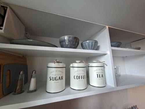 three white canisters sitting on a shelf in a kitchen at Marynarski z kuchnią i łazienką in Koszalin