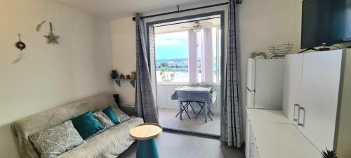 un salon avec un canapé et une porte coulissante en verre dans l'établissement Le Nid du lac 600m des plages, à Port-la-Nouvelle