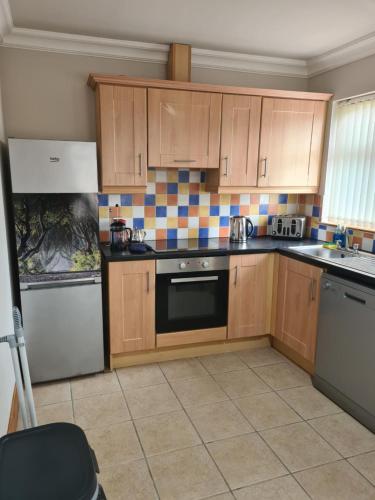 a kitchen with wooden cabinets and a stove top oven at Dark Hedges Cottage in Ballycastle
