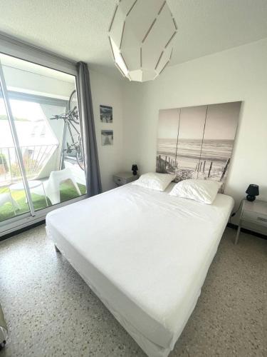 une chambre avec un lit blanc et une grande fenêtre dans l'établissement Quartier couchant Appartement t2 cabine pour 5 personnes N106, à La Grande Motte