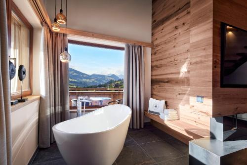 a bathroom with a tub and a large window at Der Böglerhof - pure nature spa resort in Alpbach
