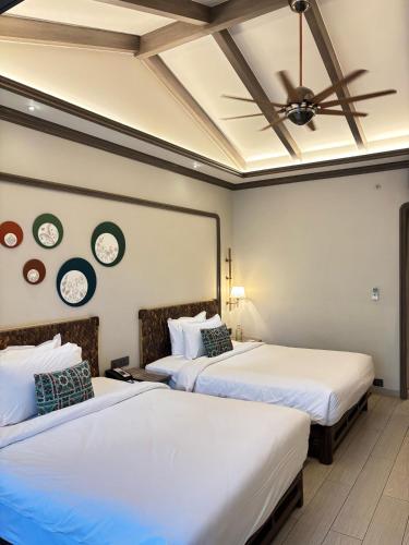 two beds in a room with two clocks on the wall at Fountain, Mahabaleshwar - IHCL SeleQtions in Mahabaleshwar