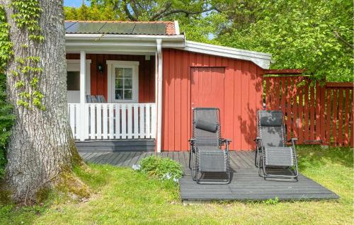 una casa rossa con sedie su una terrazza in legno di Awesome Home In Löttorp With Kitchen a Löttorp
