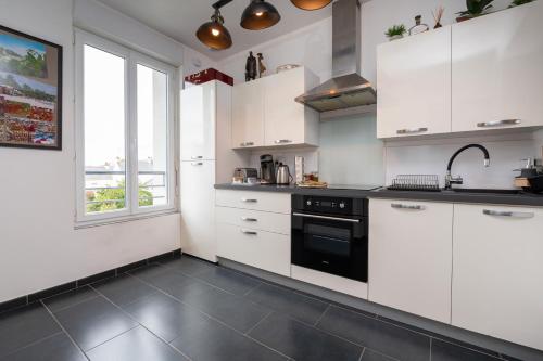 une cuisine avec des armoires blanches et un four noir dans l'établissement La Désirade - Ilots de Merville, à Lorient