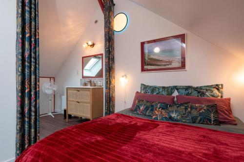 a bedroom with a red bed with a red comforter at La Désirade - Ilots de Merville in Lorient