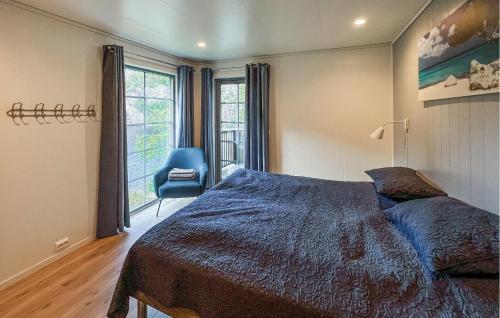 a bedroom with a bed and a blue chair at Lovely Home In Flekkefjord With Sauna in Flekkefjord