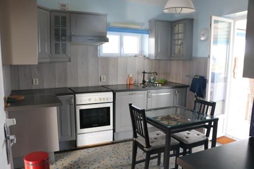 プルガヌーにあるMaison de vacances vue mer et campagneのキッチン(グレーのキャビネット、テーブル、椅子付)