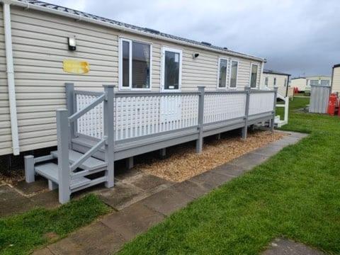a mobile home with a fence in a yard at Kingfisher Surf Shack 8 Berth Central Heated Close to site entrance FREE WIFI in Ingoldmells