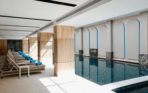 Una piscina con sillas y agua en un edificio. en Grand VM Conference & SPA, en Golem