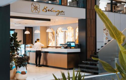 Un hombre de pie en un mostrador de un restaurante. en Grand VM Conference & SPA, en Golem
