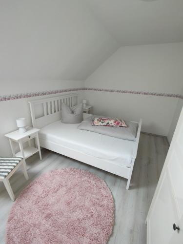 a white bed in a room with a pink rug at Urlaubszuhause 