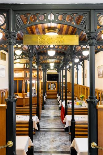 a restaurant with a long corridor with tables and chairs at Hotel Pannonia in Miskolc