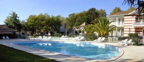 une grande piscine avec des chaises et une maison dans l'établissement Villa Naiades, à Soulac-sur-Mer