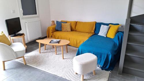 a living room with a yellow couch and a table at Petite maison cosy avec jardin in Gujan-Mestras