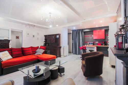 een woonkamer met een rode bank en een tafel bij Studio spacieux pour 4 personnes in Clermont-Ferrand
