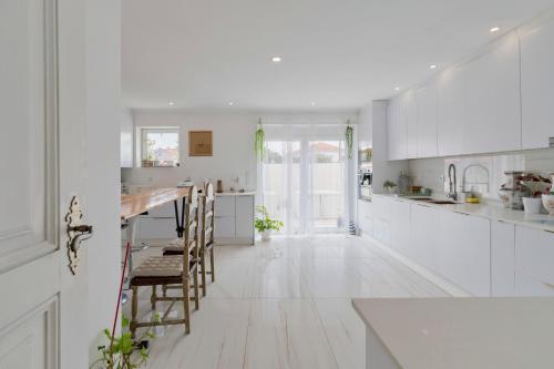 a white kitchen with white floors and white cabinets at Lovely House in Setúbal