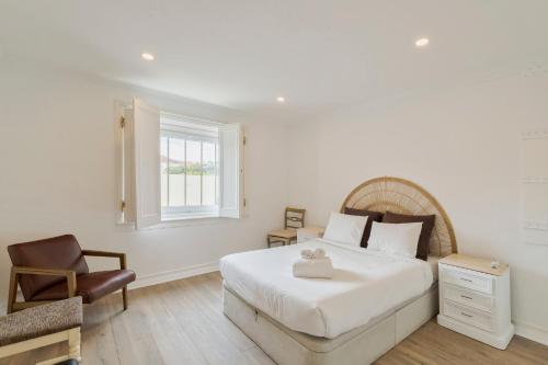 a bedroom with a large white bed and a chair at Lovely House in Setúbal