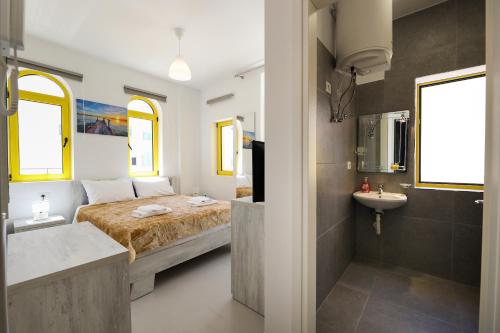 a bedroom with a bed and a sink and a bathroom at Santorini Residence, Drymades Dhermi in Gjilek