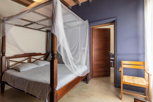 a bedroom with a canopy bed and a chair at Beau gite avec couloir de nage in Le Garn