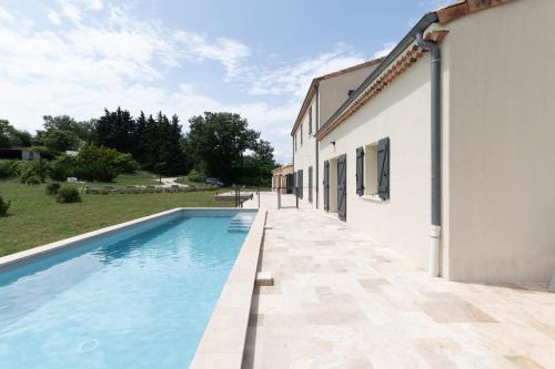 a villa with a swimming pool next to a building at Beau gite avec couloir de nage in Le Garn
