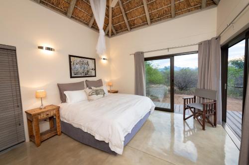 Un dormitorio con una cama y una ventana grande. en Villa Marula, en Hoedspruit