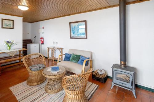 a living room with wicker chairs and a wood stove at Quinta das Queimadas in Nordeste