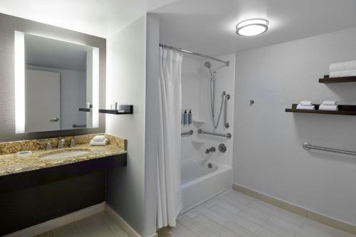 a bathroom with a shower and a sink and a tub at Courtyard by Marriott Pleasanton in Pleasanton