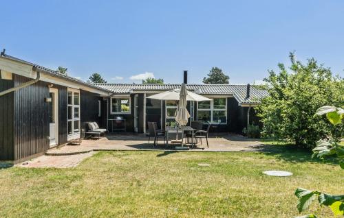 a house with a patio with a table and an umbrella at 3 Bedroom Lovely Home In Rødby in Rødby