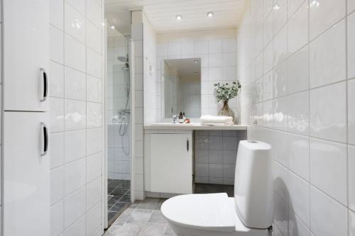 a white bathroom with a toilet and a sink at Attractive and central apartment in Ålesund