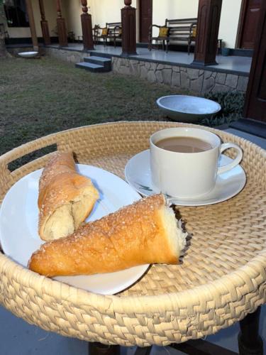 a table with a cup of coffee and a plate of bread at Illukawela Walauwa in Embilipitiya