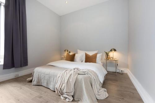 a white bedroom with a bed with a blanket on it at Attractive and central apartment in Ålesund