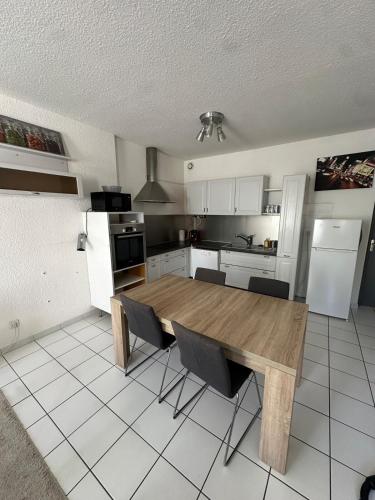 une cuisine avec une table en bois et un réfrigérateur dans l'établissement Joli T3 Proche de l'hôpital, à La Tronche