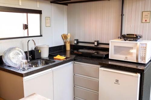 a kitchen with a microwave and a sink at Studio 7 completo com Wifi no 1º Andar Novo in Curitiba