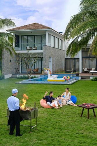 a group of people sitting around a barbecue in a yard at Renaissance Danang Hoi An Resort & Spa in Hoi An