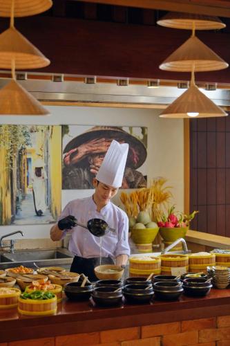 a chef standing in a kitchen preparing food at Renaissance Danang Hoi An Resort & Spa in Hoi An