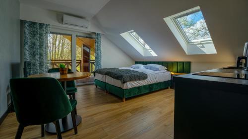 a bedroom with a bed and a table and a kitchen at Villa Park Zwierzyniec in Zwierzyniec