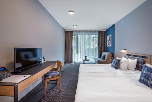 a hotel room with a large bed and a desk at Парк Хотел Модър in Devin