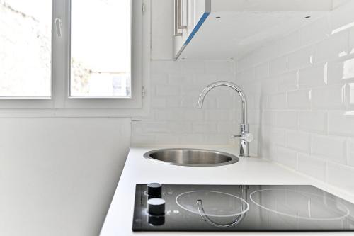 une cuisine blanche avec un évier et une fenêtre dans l'établissement Ravissant appartement à Paris 14ème-IV, à Paris