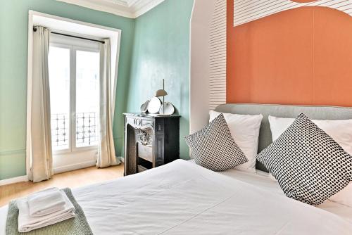 une chambre avec un grand lit blanc et une fenêtre dans l'établissement Ravissant appartement à Paris 14ème-IV, à Paris
