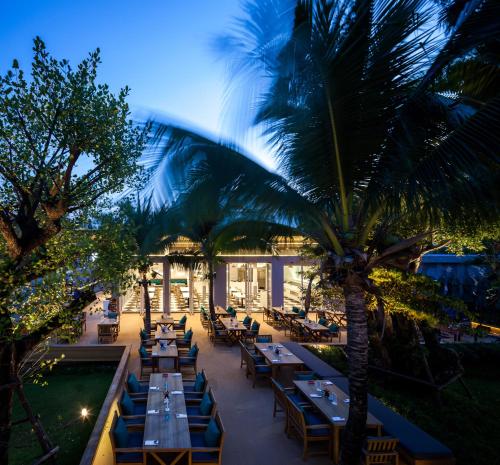 a restaurant with tables and palm trees at night at Bann Pantai Resort in Cha Am