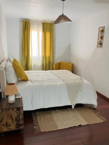 a bedroom with a bed with white sheets and yellow curtains at Villa la Gardiole in Vic-la-Gardiole
