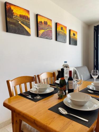 a wooden table with plates and wine glasses on it at Seafront Maisonette Ocean Views & Terrace in Mellieħa