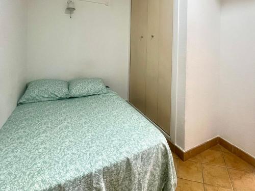 - une petite chambre avec un lit et une couette verte dans l'établissement Antinéa - Clarté, Calme et Confort à 200m de la Plage avec Parking, à La Grande Motte